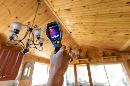 Indoor damp & air quality (IAQ) testing. A close up and low angle view on the hand of a home inspector at work inside a residential property, checking the air temperature and quality, with copy-space.