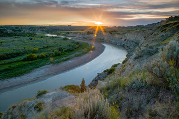 The Sun sets over the Little Missouri River and Wind Canyon, Theodore Roosevelt National Park,...