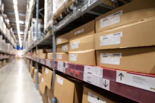 blurred brown goods boxes on full shelves in warehouse storage factory . perspective background with space for business about logistics shipping and wholesale concept .