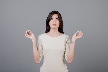 beautiful brunette woman meditating with om gesture isolated over grey