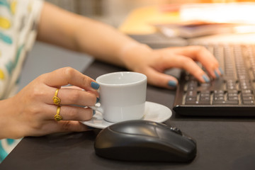 Woman hand holdding coffee cup with working table