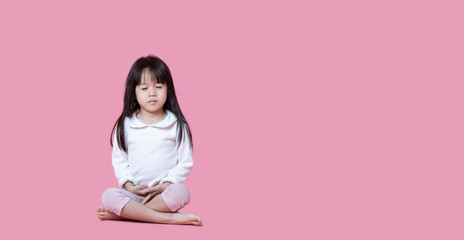 Asian children cute or kid girl sit for meditation with peace and relax on pink background at...