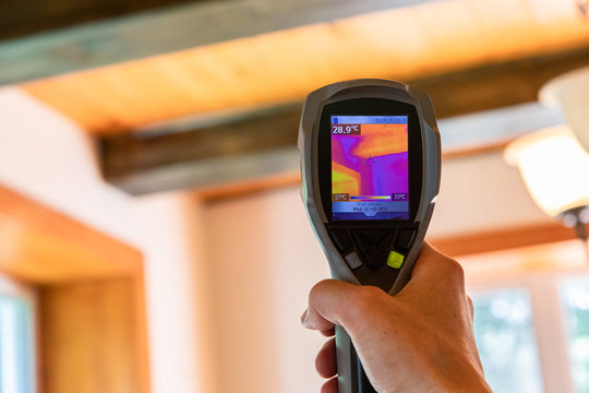 Indoor damp & air quality (IAQ) testing. An infrared thermal imaging device is seen in use, close up during an indoor environmental quality and regulation assessment, with copy space.