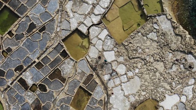 People walk among the ancient Salt Pans on the island of Gozo in Malta as seen from above.
