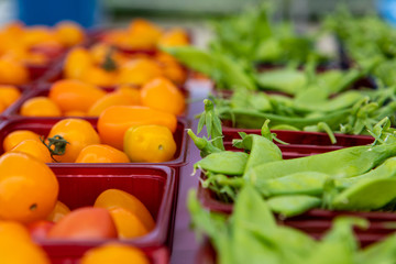 Organic produce at a farmer's market. A closeup view of small trays of yellow tomatoes and green...