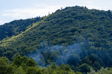 Fototapeta na wymiar The beginning of the fire in the mountain forests, smoke rises above the trees