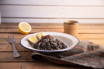 Plate of black rice with squid and prawns or Valencian black paella