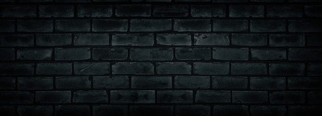 Old shabby black brick wall texture. Cement block dark widescreen backdrop. Gloomy grunge wide...