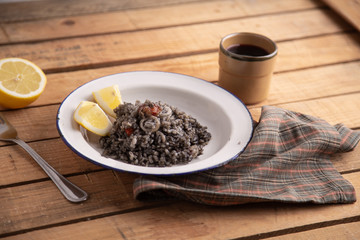 Plate of black rice with squid and prawns or Valencian black paella