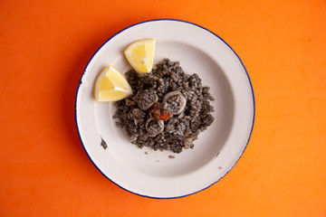 Plate of black rice with squid and prawns or Valencian black paella