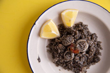 Plate of black rice with squid and prawns or Valencian black paella