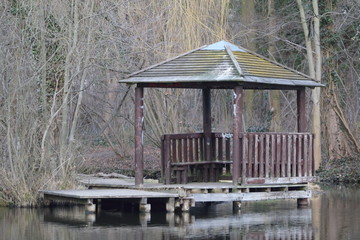 Fototapeta na wymiar An old wooden gazebo with jetty built close to a lake shore