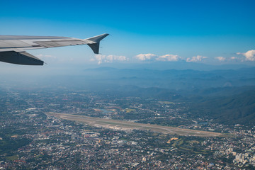 Naklejka na ściany i meble Chiang Mai International Airport and surrounding area with clear blue sky view from airplane window