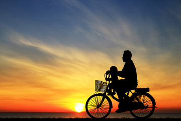 Fototapeta na wymiar silhouette Father and son riding bicycle at sunset sky