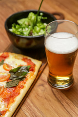 Homemade pizza served with a bowl of green salad on the wooden table	
