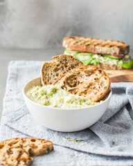 Green beans hummus with toasts on a wooden board on a light background