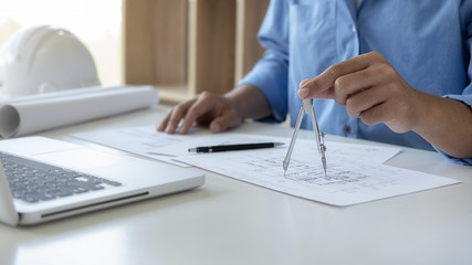 Architect or Engineer working in office with engineering tools, blueprint and building model....