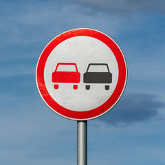 No overtaking road traffic sign on background of blue sky with clouds. Warning and information road...