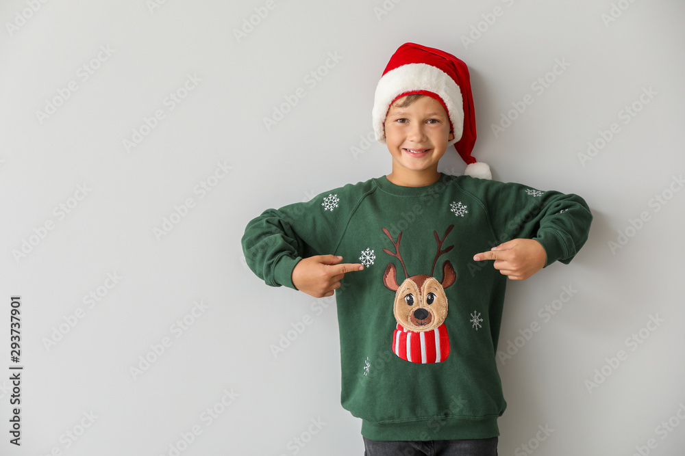 Canvas Prints Funny boy in Christmas sweater and Santa hat on light background