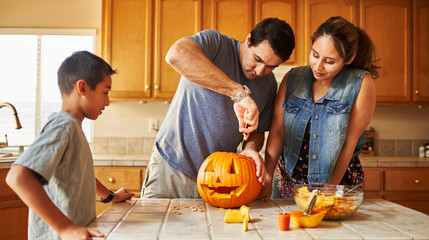 halloween activity - family carving pumpkin into jack-o-lantern