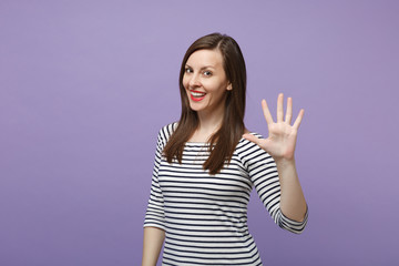 Pretty young woman in casual striped clothes posing isolated on violet purple background studio portrait. People sincere emotions lifestyle concept. Mock up copy space. Showing palm spreading fingers.