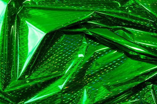 Creative photo background of green crumpled foil with highlights and shadows