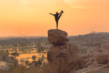An Acrobat performs acrobatics at the spectacular sunset point at Hampi in Karnataka, India. Acro yoga , bouldering and music performers enjoy daily sunset here. Gymnasts outdoor
