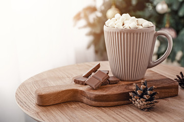 Cup of hot chocolate and marshmallows on table in room