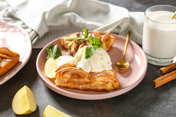 Plate with pieces of apple pie and ice cream on dark background