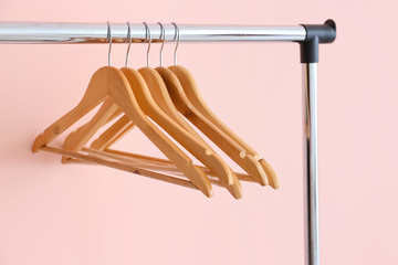 Rack with clothes hangers on color background