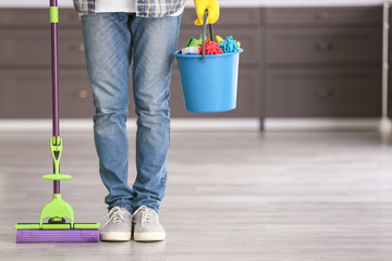 Young man with cleaning supplies at home