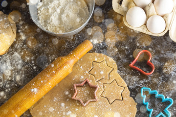 Cooking Christmas gingerbread cookies with ingredients on a dark background