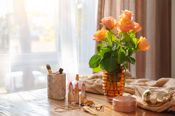 Rose flowers with makeup cosmetics on wooden table in room