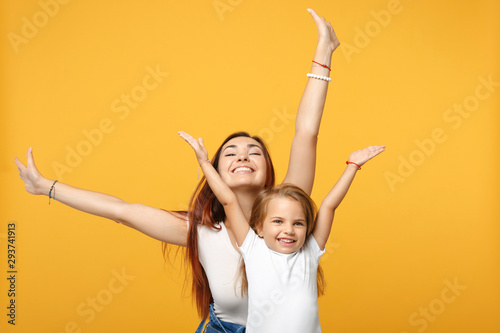 Woman in light clothes have fun with cute child baby girl 4-5 years old. Mommy little kid daughter isolated on yellow background studio portrait. Mother's Day love family parenthood childhood concept.