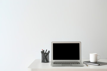 Modern workplace with laptop near white wall