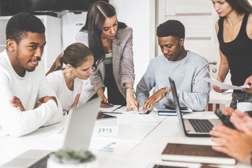 A team of young office workers, businessmen with laptop working at the table, communicating together in an office. Corporate businessteam and manager in a meeting. coworking.