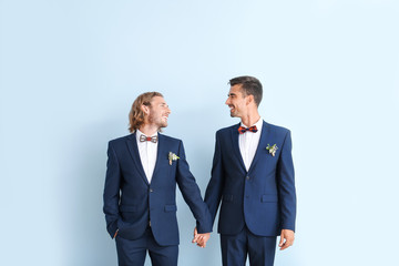 Portrait of happy gay couple on their wedding day against color background