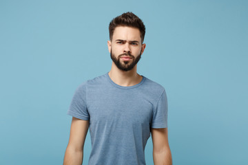 Young confused pensive displeased man in casual clothes posing isolated on blue wall background, studio portrait. People sincere emotions lifestyle concept. Mock up copy space. Looking camera.