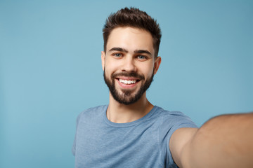 Close up Young smiling man in casual clothes posing isolated on blue wall background, studio...