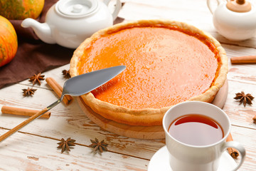Tasty pumpkin pie and cup of tea on wooden table