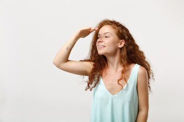 Young charming redhead woman in casual light clothes posing isolated on white background in studio. People lifestyle concept. Mock up copy space. Hold hand at forehead looking aside far away distance.