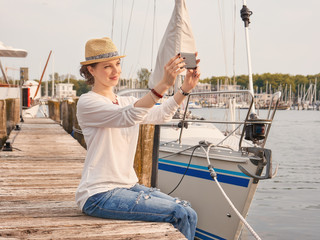 Fototapeta na wymiar Woman in seaport making selfie with yachts on background.