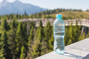 Transparent plastic A bottle of clean water with a blue lid stands on wood board. The concept of...