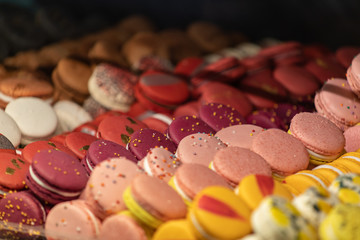 Colorful cakes macaron aka French macarons lie on the counter. Multi-colored macarons lie in rows.
