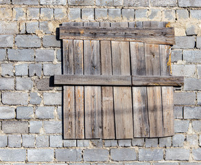 The windows of a brick house boarded up with wooden boards