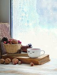 Cup of tea, books, nuts and sweater on background of winter frost window. sweater weather, cozy home, winter season background. comfort, relaxing in cold snowy weather at home. soft selective focus