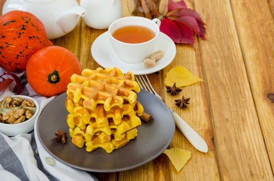 Stack of spicy pumpkin waffles on a dark plate with caramel sauce and whipped cream on a dark wooden background.  Rustic style. Fragrant autumn breakfast. Breakfast for Halloween.