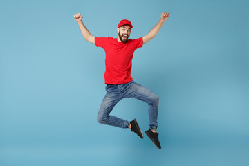 Delivery man in red uniform workwear isolated on blue wall background, studio portrait. Professional male employee in cap t-shirt print working as courier dealer. Service concept. Mock up copy space.