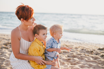 Young motherand her little sons on beach at sunset