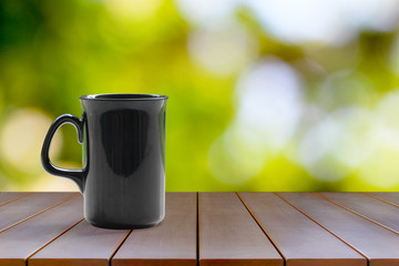 A black coffee mug on a wooden table On a natural background